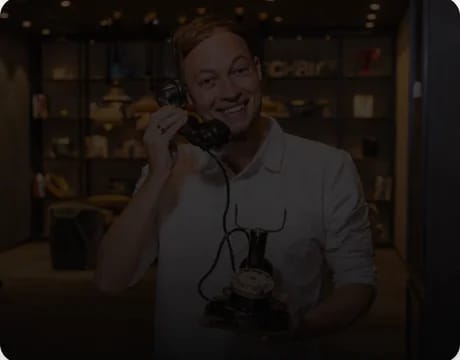 Lächelnder Mann mit dem Hörer eines alten Wählscheibentelefons am Ohr